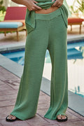 Close-up of green cotton crochet wide-leg pants with elastic waistband worn beside a pool
